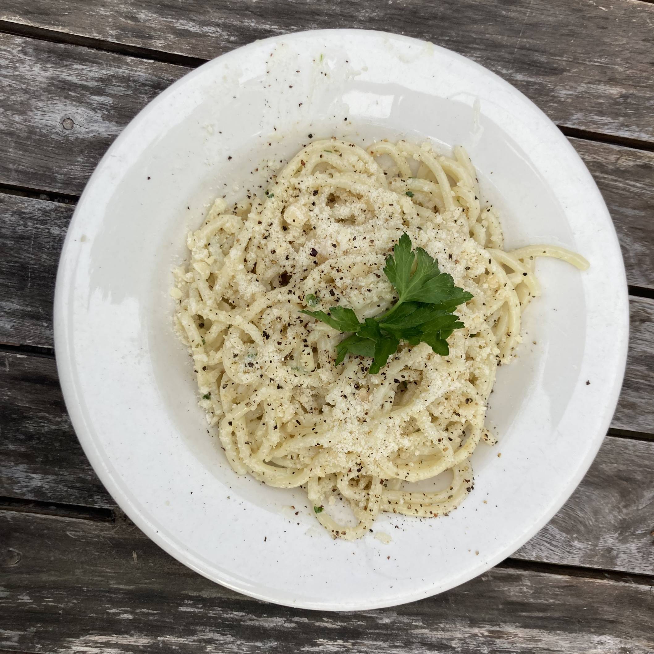 top down photo of some spaghetti with garlic butter sauce, black pepper, parmesan, and cilantro.
